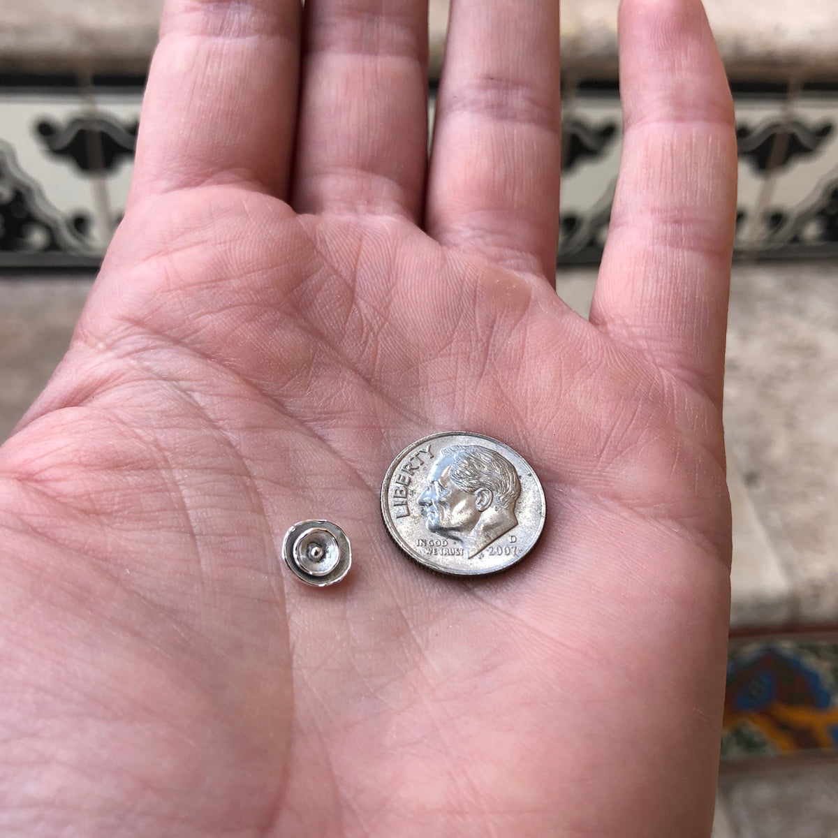 silver flower casting next to dime